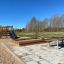 Holz-Sandkasten im Freien mit Rutsche und Sitzbänken auf einem Spielplatz.