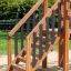 Holztreppe des Spielplatzgerüsts Brücke II mit Metallstützen und Rutsche im Hintergrund.