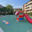 Kleiner Dschungel Klettergerüst mit Rutsche auf einem Spielplatz mit weichem Boden und Schaukeln im 