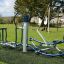 Outdoor-Fitnessgeräte Set 8 im Park, mit blauen und silbernen Elementen.