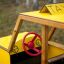 Kinderspielhaus im Taxi-Design mit gelber Farbe und rotem Lenkrad.