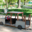 Spielhaus im Freien, gestaltet wie ein Auto mit Lenkrad und Sitzbänken, auf einem Spielplatz.
