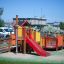 Barrierefreier Spielplatz von Gamma mit Rutsche und bunten Spielgeräten.