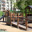 Barrierefreier Spielplatz von Gamma mit Rutsche und Holzspielhaus in einem Park.