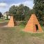 Holzspielhäuser in Wigwam-Form auf einem Spielplatz im Freien.
