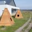 Dreieckige Wigwam Spielhäuser aus Holz im Außenbereich eines modernen Gebäudes.