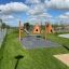 Spielplatz mit zwei Wigwam Spielhäusern und einer Schaukel auf grünem Gras.
