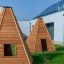 Holzspielhaus Wigwam im Garten vor modernem Gebäude.