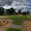 Outdoor-Spielplatz mit Klettergerüsten und Balancierbalken auf Kiesplatz.