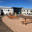 Holzspielplatz im Freien vor modernem Schulgebäude