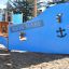 Blauer König Spielschiff mit Spiralrutsche auf einem Spielplatz mit Sandboden.
