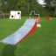 Rote und graue Rampe im Freien auf grünem Gras für Kinder-Spielplatz.