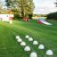Spielplatzgerät Rampe im Freien mit Rutsche und Kletterelementen auf grünem Rasen.