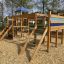 Spielkombination mit Spielturm, Rutsche und Kletterelementen auf einem Spielplatz.