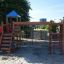 Spielkombination mit Spielturm, Rutsche und Kletterelementen auf einem Sandplatz.