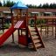 Spielkombination mit Spielturm und Rutsche im Außenbereich auf Sandplatz.