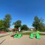 Spielplatz mit grünen Umbrela-Sitzgelegenheiten und rotem Dach im Park.