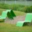 Moderne grüne Sofa im Freien auf dem Spielplatz mit Gras und Pflanzen.