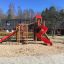 Spielplatz mit Twister Spielanlage, Rutsche und Kletterturm auf Sandboden.