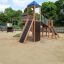 Kinder-Spielanlage Twister Spielanlage mit Rutsche auf einem Spielplatz mit Sandboden, umgeben von G