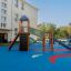 Twister Spielanlage mit Rutsche und Kletterwand auf einem Spielplatz mit blauer Fallschutzmatte.