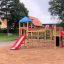 Holzspielplatz mit Rutsche, Klettergerüst und Spielturm in einem Sandbereich
