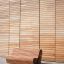 Moderne Holzbank Sofa Wave vor einer Holzwand in städtischer Umgebung.