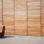 Moderne Sofa Wave aus Holz vor einer horizontalen Holzwand.