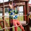 Junge spielt an einem Kletterseil auf einem Spielplatz von Tarzan Spielanlage mit Spielturm, Tunnel 