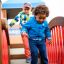Kinder spielen auf der Tarzan Spielanlage mit Spielturm, Tunnel und Rutsche auf einem Spielplatz.