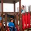 Kinder spielen auf einem Tarzan Spielanlage mit Spielturm, Tunnel und Rutsche auf einem Spielplatz.