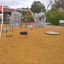 Doppel Reifenschaukel Solaris auf Kinderspielplatz mit Sandboden und Kletterfelsen im Hintergrund.