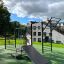 Outdoor-Fitnessgerät New Age Fit MEDIUM in einem Park mit Rutsche und Kletterwand.