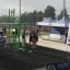 Menschen trainieren an Outdoor-Fitnessgeräten beim Sportevent mit New Age Fit Banner im Hintergrund.