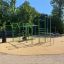Freiluft-Fitnessgeräte New Age Fit auf einem sonnigen Spielplatz mit grüner und blauer Ausrüstung.