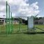 Grünes Freiluftsportgerät New Age Fit auf Rasenplatz.