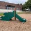 Kinder-Rutsche mit Drachenschwanz-Design auf einem Spielplatz.