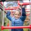 Mädchen spielt auf einem Klettergerüst mit Rutschstange auf einem Spielplatz.