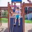 Kinder spielen auf Weltraumstation mit Spieltürmen und Spiralrutsche auf Spielplatz