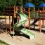Weltraumstation mit Spieltürmen und grüner Spiralrutsche auf einem Spielplatz