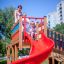 Kinder spielen auf einer Weltraumstation mit Spieltürmen und Spiralrutsche auf einem Spielplatz.