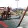 Spielplatz mit Fallschutzplatte 55 und Rutsche aus Holz und Metall in einem urbanen Park.