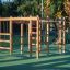 Holz-Spielgerüst Schimpanse Klettergerüst auf einem Spielplatz mit grünem Boden.