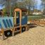 Traktor Spielhaus mit Anhänger auf einem Spielplatz mit Holzhackschnitzel.
