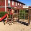 Spielplatzgerät mit Kletterwand, Rutsche und Kletternetz im Freien.