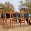 Spieltürme mit Tunnel, Kletterwand, Rutsche und Schaukel auf einem Kinderspielplatz.