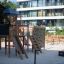 Spieltürme mit Tunnel, Kletterwand und Rutsche auf einem modernen Spielplatz aus Holz vor Wohngebäud