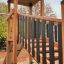 Spielturm mit Rutsche, Kletterwand und Tunnel aus Holz im Außenbereich.