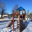 Kinderspielplatz Logo Spielturm mit Feuerwehrstange im Winter, mit Schaukel und Rutsche auf schneebe