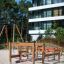 Kleine Fitnessanlage aus Holz mit Balancier- und Kletterelementen auf Sandboden vor modernem Wohnhau